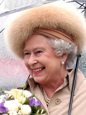Photo of Queen in the rain wearing fur hat holding flowers and an umbrella.  Item # GR2012.0472-168.0011